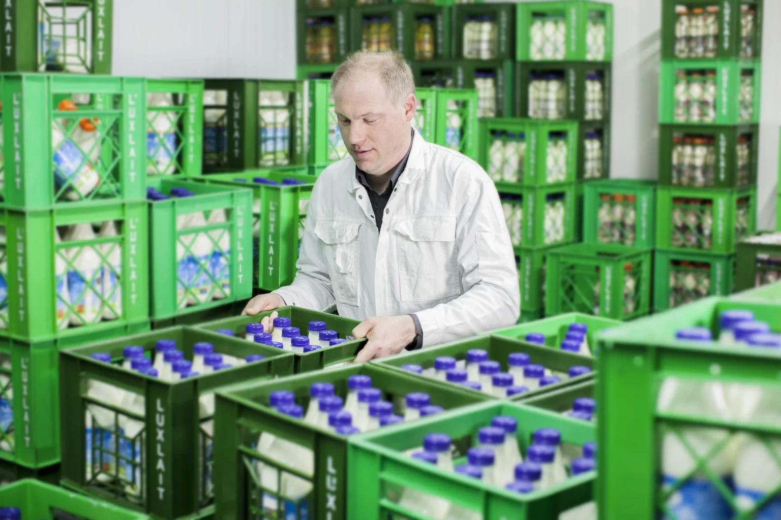 Foto: Mitarbeiter stapelt Kisten mit vollen Milchflaschen (© Ernährung-NRW e. V.)